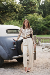a lady in a floral printed shirt and a pair of white pants